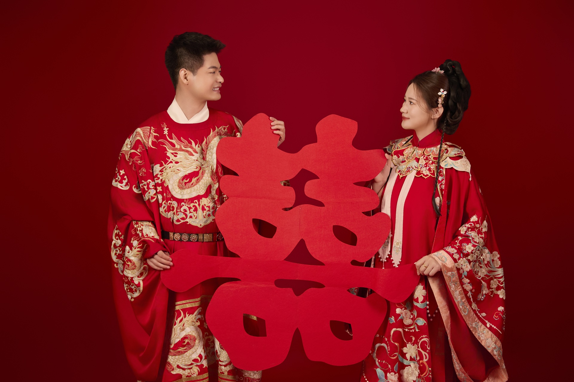 刘鑫与阚丽娜在喜庆红色棚景中合影